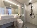 Modern bathroom with well-lit vanity, glass shower, and sleek fixtures