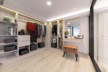 Modern bedroom walk-in closet with built-in shelving and seating area