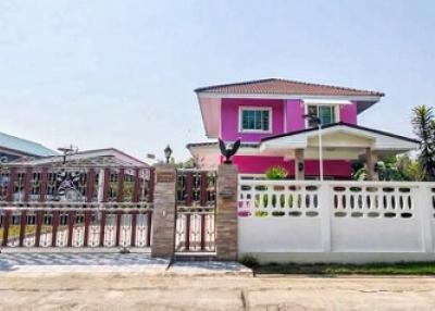 Bright pink two-story house with gated entrance and tropical plants