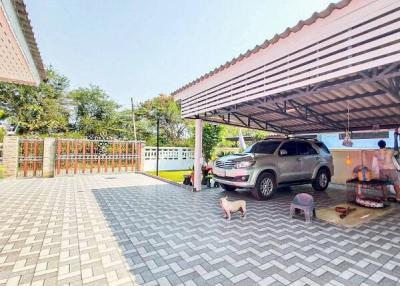 Spacious paved driveway with a carport and fenced lawn