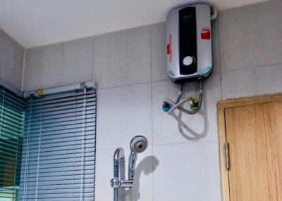 Electric water heater and shower head in a bathroom with tiled walls