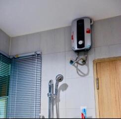 Electric water heater and shower head in a bathroom with tiled walls