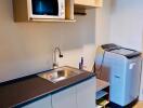 Compact modern kitchen with stainless steel countertop, microwave, and portable washing machine