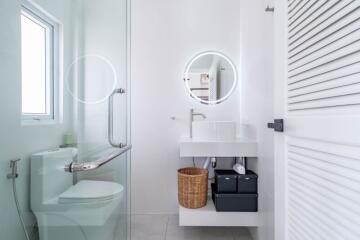 Modern bathroom with clean white design, illuminated mirror, and a glass shower