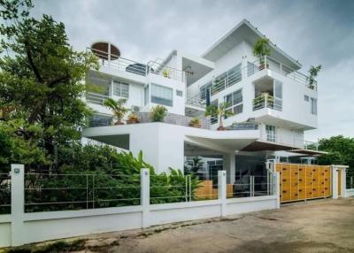 Modern multi-story residential building with balconies and lush greenery