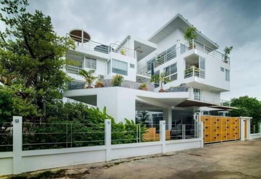 Modern multi-story residential building with balconies and lush greenery