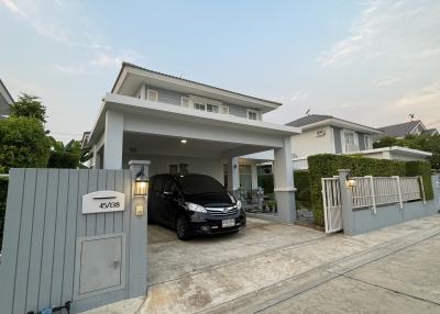 Spacious two-story house with a carport and a car parked under it