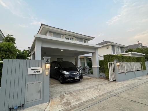 Spacious two-story house with a carport and a car parked under it