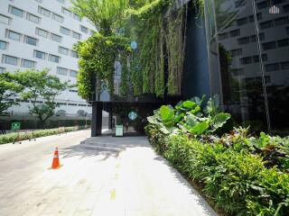 Modern building entrance with lush greenery and glass facade
