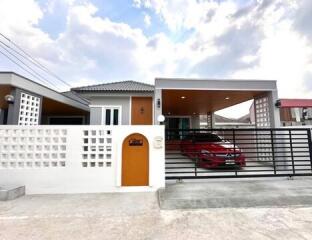 Modern single-story house exterior with carport and gated entrance