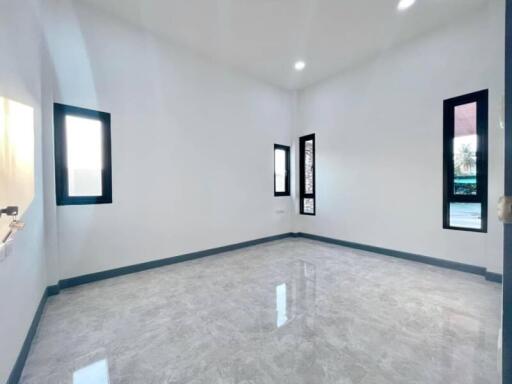 Spacious empty room with glossy tiled flooring and natural light