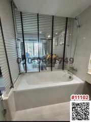 Modern bathroom interior with a large bathtub, window blinds, and tiled walls