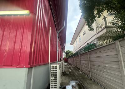 Narrow space between two buildings with a red corrugated fence on one side