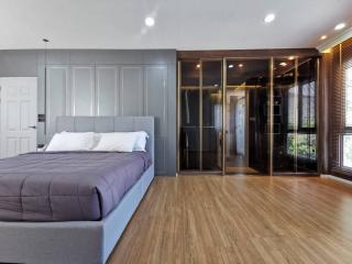 Modern bedroom interior with wooden floor, large bed, and built-in closet