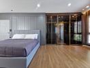 Modern bedroom interior with wooden floor, large bed, and built-in closet