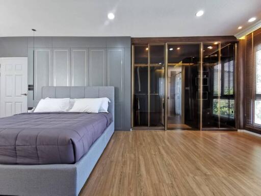 Modern bedroom interior with wooden floor, large bed, and built-in closet