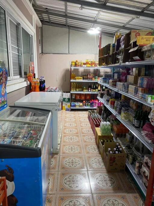 Well-stocked small grocery store interior with various products and freezer