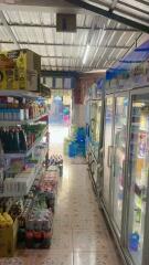 Interior view of a small convenience store with refrigeration units and shelves stocked with goods
