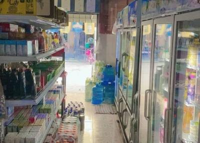 Interior view of a small convenience store with refrigeration units and shelves stocked with goods