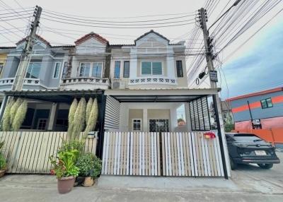 Exterior view of a two-story residential townhouse with balcony and gated entrance