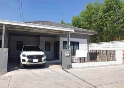 Modern single-story house with a car parked in the driveway and a fenced yard