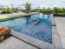 Modern outdoor swimming pool with blue tiles and surrounding garden area