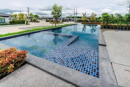 Modern outdoor swimming pool with blue tiles and surrounding garden area