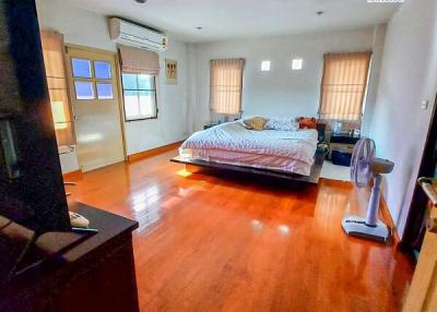 Spacious bedroom with wooden flooring and ample natural light