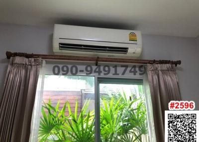 Air conditioning unit above window with curtains and view of greenery
