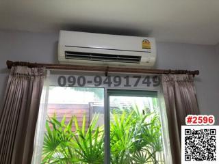 Air conditioning unit above window with curtains and view of greenery