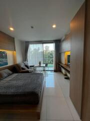 Modern bedroom with integrated living area featuring a large bed, sofa, and flat-screen TV