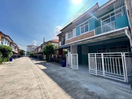 Townhouses with blue sidings along a street under clear skies