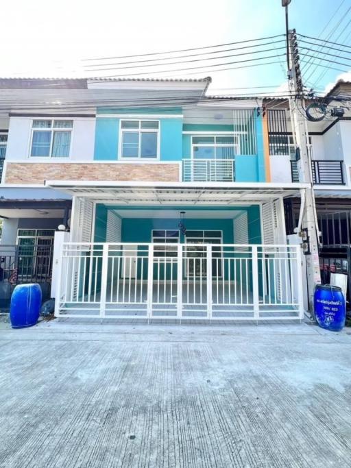 Two-story residential townhouse with blue accents and frontal parking