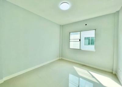 Bright empty bedroom with a large window and glossy tiled floor