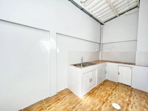 Compact kitchen with wooden countertops and white cabinetry under a sloped ceiling