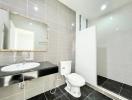 Modern bathroom with neutral color palette, featuring a large mirror, sink, and toilet