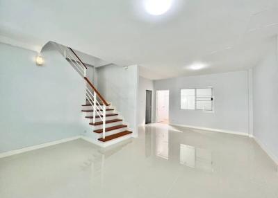 Spacious and bright living area with a modern staircase and glossy floor tiles