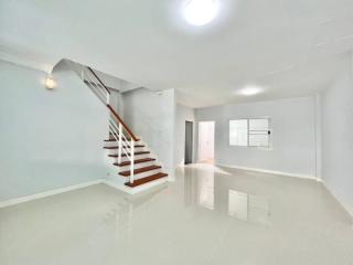 Spacious and bright living area with a modern staircase and glossy floor tiles