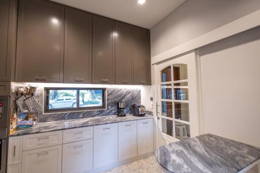 Modern spacious kitchen with marble countertops, upper cabinets, and built-in appliances