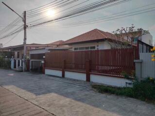 Exterior view of a residential house with fenced yard and tiled roof