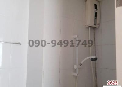 Compact bathroom with white tiles and wall-mounted electric shower