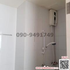 Compact bathroom with white tiles and wall-mounted electric shower