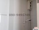 Compact bathroom with white tiles and wall-mounted electric shower