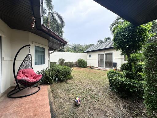 Cozy backyard with lawn, hanging chair, and garden - view towards a detached house