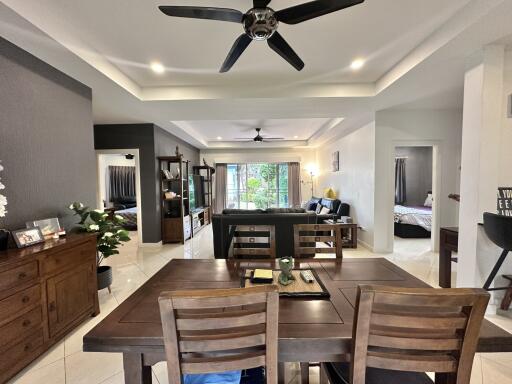 Spacious dining room with adjoining living room, featuring a modern dining set, ceiling fan, and ample natural light