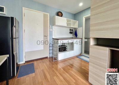 Modern kitchen with wood flooring, white cabinetry, stainless steel refrigerator, and built-in microwave