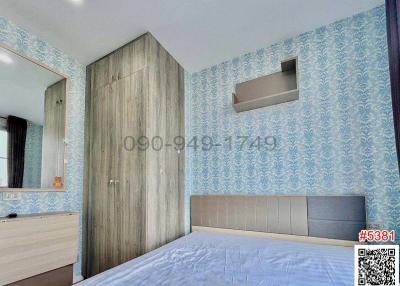 Cozy bedroom with wooden wardrobe and blue patterned wallpaper