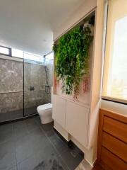 Modern bathroom with green wall, a glass shower cabin, and natural light