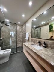 Modern bathroom with spacious glass shower, sleek design, and well-lit vanity area