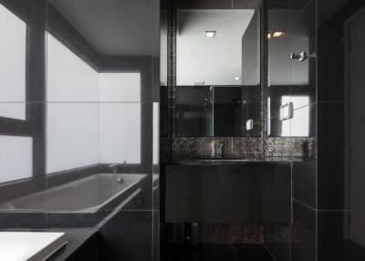 Modern bathroom interior with dark tiles featuring a bathtub and a vanity